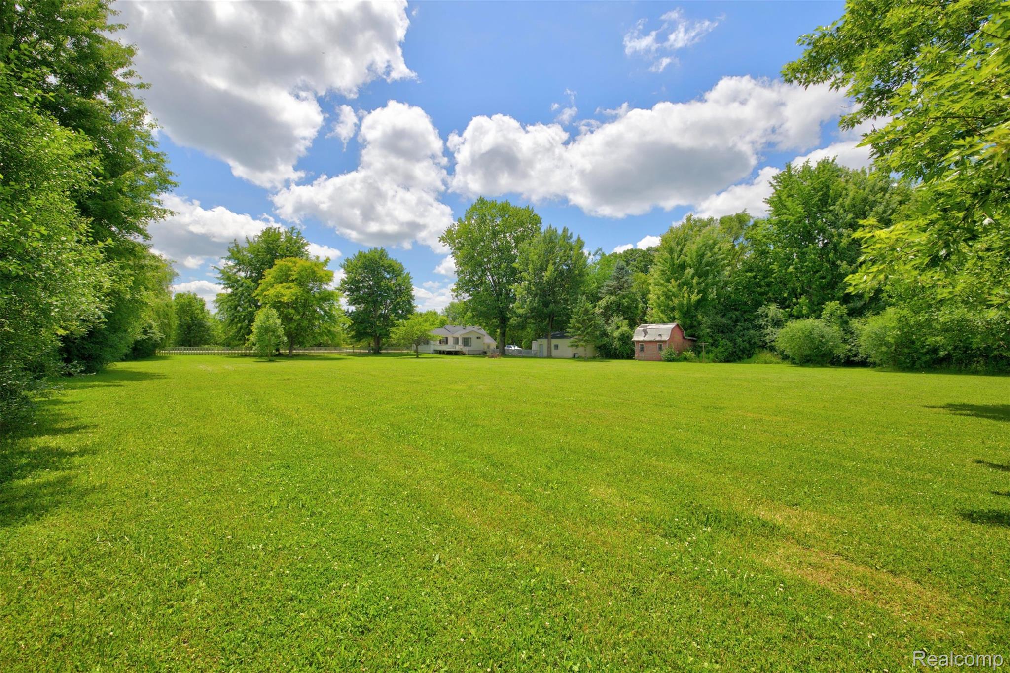 5244 Oleksyn Road Flint, MI 48504 - Photo 55 of 70 Expansive green lawn surrounded by mature trees, featuring a light-colored residence with a dark roof and a separate red brick outbuilding