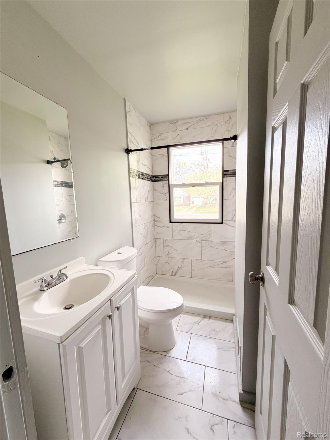 15815 Evergreen Road Detroit, MI 48223 - Photo 7 of 12 Bathroom featuring a white vanity with integrated sink, chrome faucet, and white paneled cabinetry