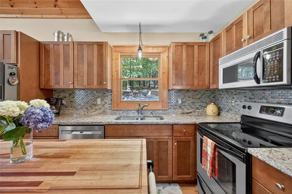 a kitchen with stainless steel appliances granite countertop a stove a sink and a microwave