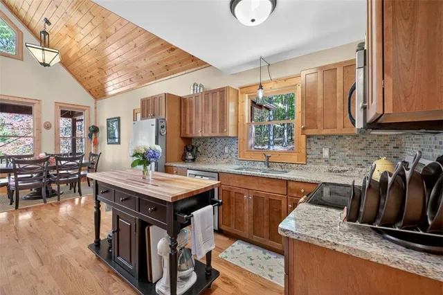 a kitchen with granite countertop a refrigerator a sink dishwasher and wooden cabinets with wooden floor