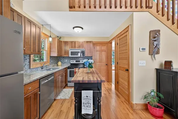 a kitchen with granite countertop a refrigerator a sink dishwasher and wooden cabinets with wooden floor