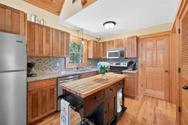 a kitchen with granite countertop a stove top oven a sink dishwasher and a refrigerator with wooden floor