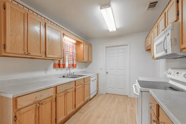 a kitchen with stainless steel appliances granite countertop a sink a stove a microwave oven cabinets and wooden floor