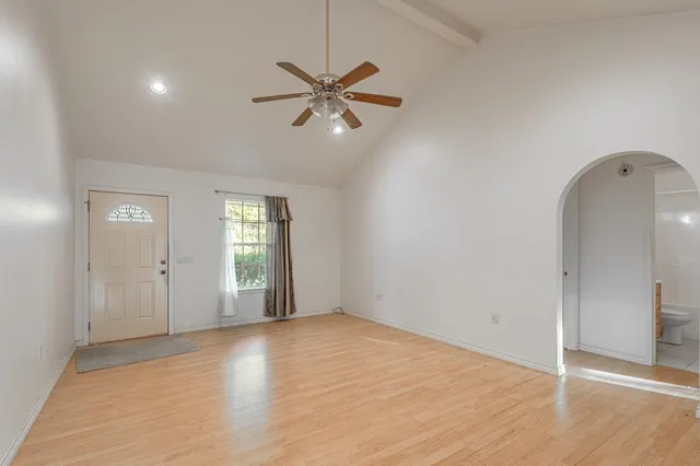 an empty room with wooden floor closet and windows