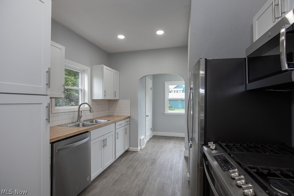 13131 Cedar Road Cleveland, OH 44118 - Photo 9 of 23 Kitchen featuring light hardwood / wood-style floors, backsplash, white cabinetry, appliances with stainless steel finishes, and sink