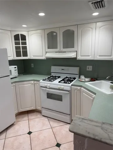 a kitchen with granite countertop a sink a stove and cabinets