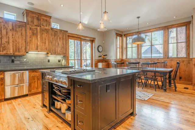 a kitchen with granite countertop a stove a sink a dining table and chairs with wooden floor