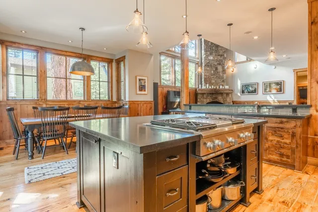 a kitchen with stainless steel appliances granite countertop a stove a sink a oven a dining table and chairs with wooden floor