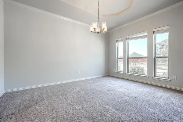 an empty room with chandelier fan and windows