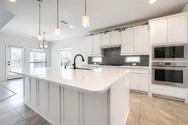 a kitchen with kitchen island granite countertop a sink a counter top space appliances and cabinets