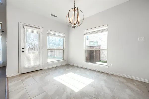 an empty room with chandelier fan and windows