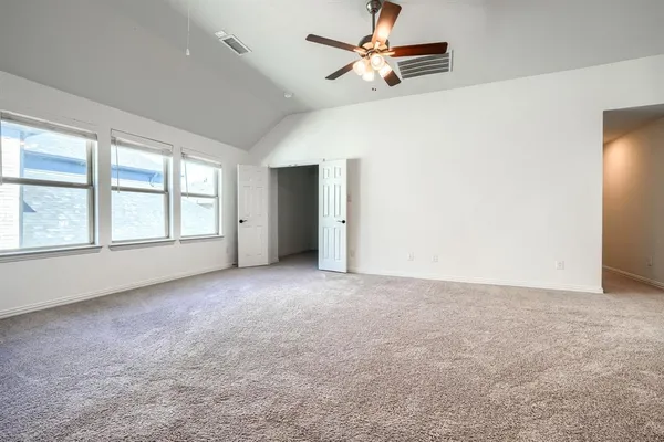 an empty room with chandelier fan and windows