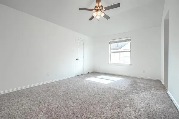 an empty room with a window and a fan