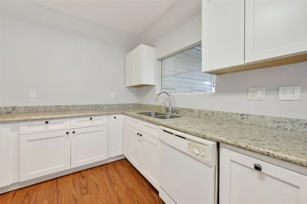 a kitchen with granite countertop white cabinets and a sink