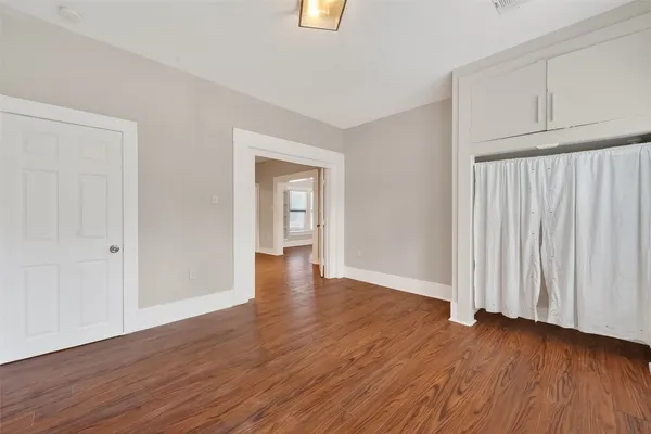 a view of an empty room with wooden floor and closet