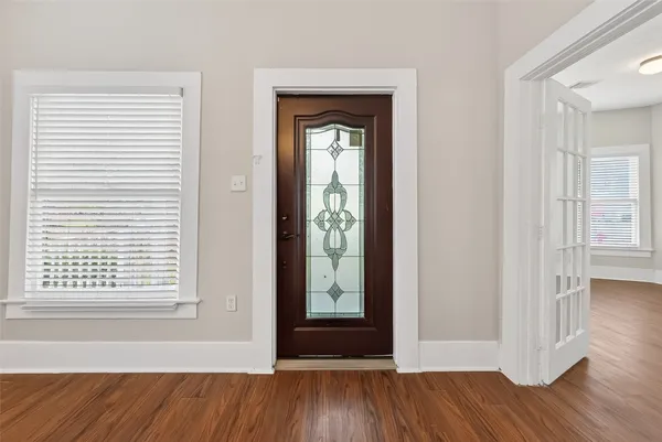 an empty room with wooden floor windows and entrance