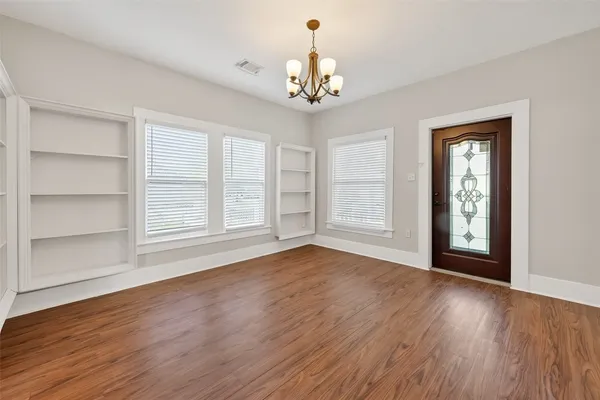 a view of an empty room with a window and wooden floor