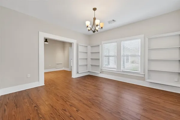 a view of an empty room with a window and wooden floor
