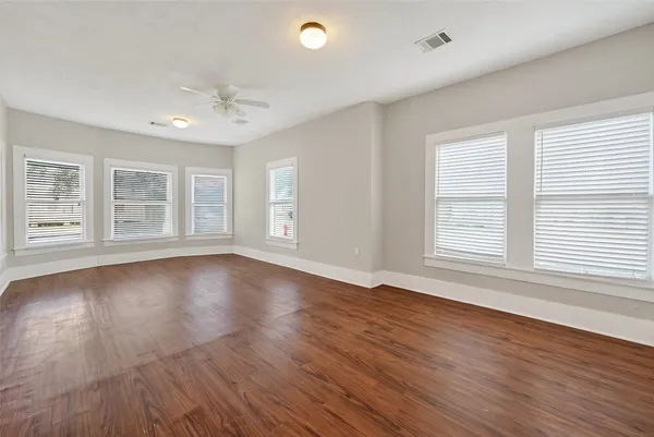an empty room with wooden floor and windows with curtains view