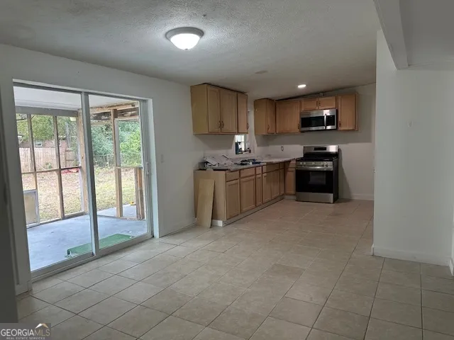 a kitchen with stainless steel appliances granite countertop a stove top oven a sink a dining table and chairs