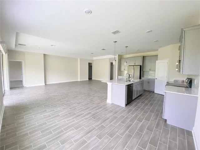 a large white kitchen with kitchen island a sink wooden floor and white stainless steel appliances