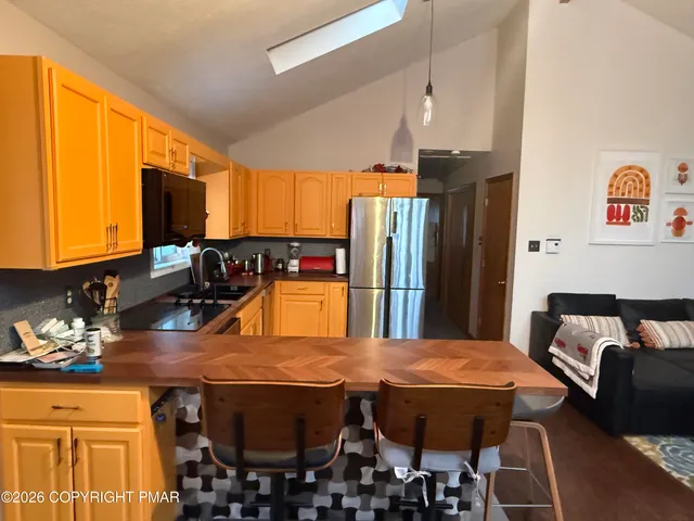 a room with stainless steel appliances kitchen island granite countertop a table chairs in it and a window