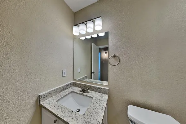 a bathroom with a granite countertop sink a toilet and a mirror