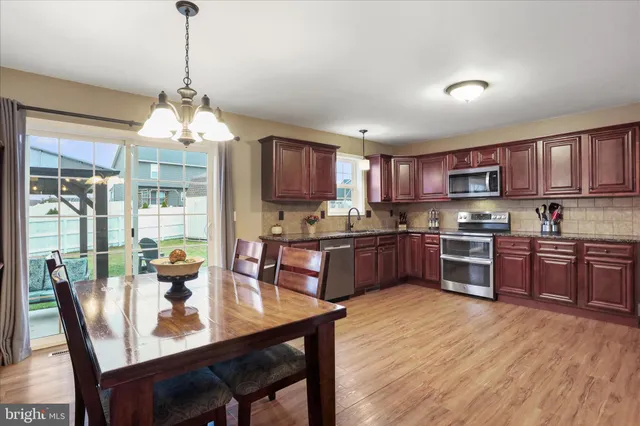 a kitchen with stainless steel appliances granite countertop wooden floors a stove a microwave a dining table and chairs