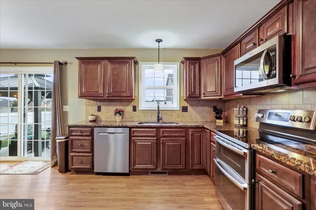 a kitchen with stainless steel appliances granite countertop a stove a sink dishwasher and a microwave oven with cabinets