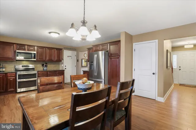 a kitchen with stainless steel appliances granite countertop a stove top oven a sink a dining table and chairs with wooden floor