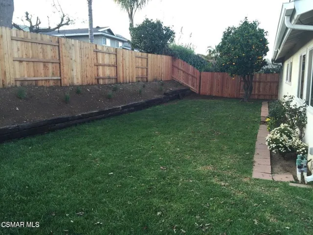 a view of a backyard with potted plants and wooden fence