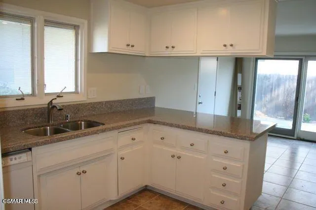 a kitchen with granite countertop white cabinets and sink
