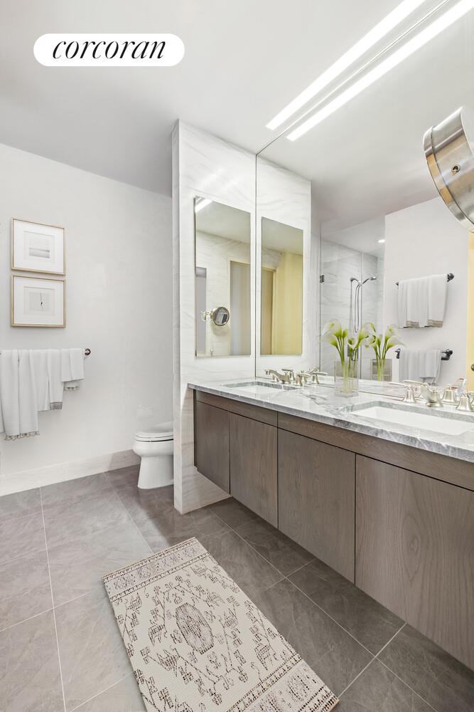 333 East 91st Street, Unit 31CD Manhattan, NY 10128 - Photo 10 of 15 a spacious bathroom with a granite countertop sink a toilet and a mirror