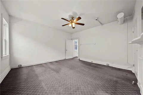 an empty room with wooden floor ceiling fan
