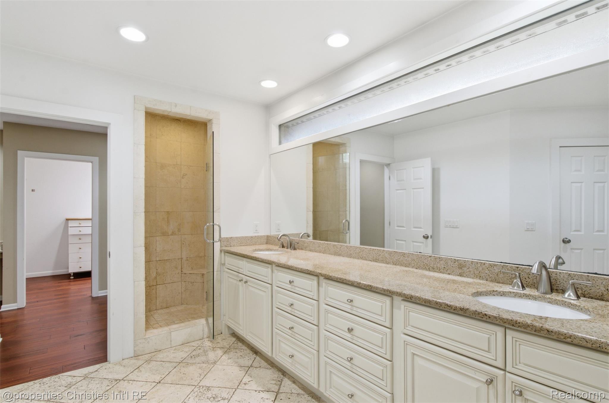 25310 Canterbury Road Franklin, MI 48025 - Photo 21 of 55 Spacious bathroom featuring a dual vanity with light-toned countertops, tiled flooring, an enclosed shower with natural stone-look tiling, and recessed lighting