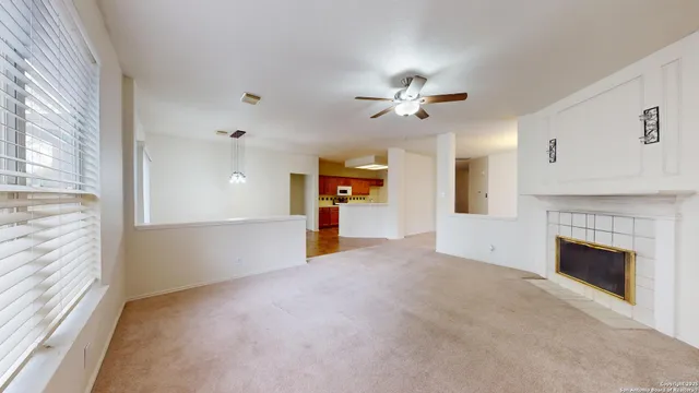 a view of a livingroom with a fireplace a ceiling fan and windows