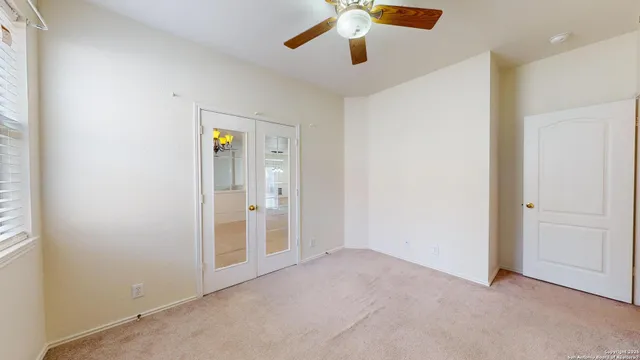 an empty room with closet and a chandelier fan