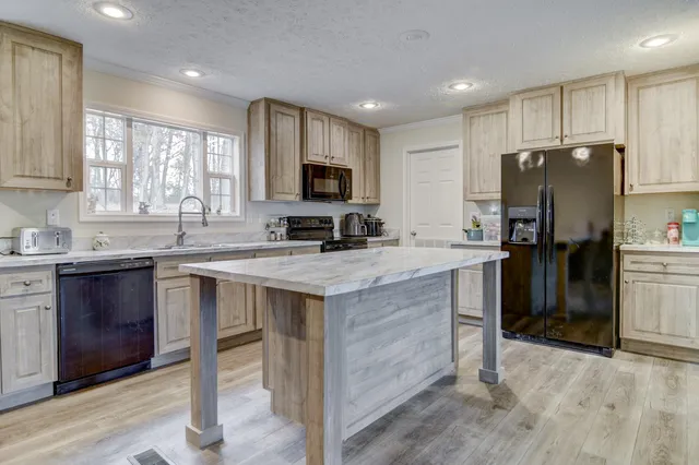 a kitchen with granite countertop a refrigerator stove top oven and sink
