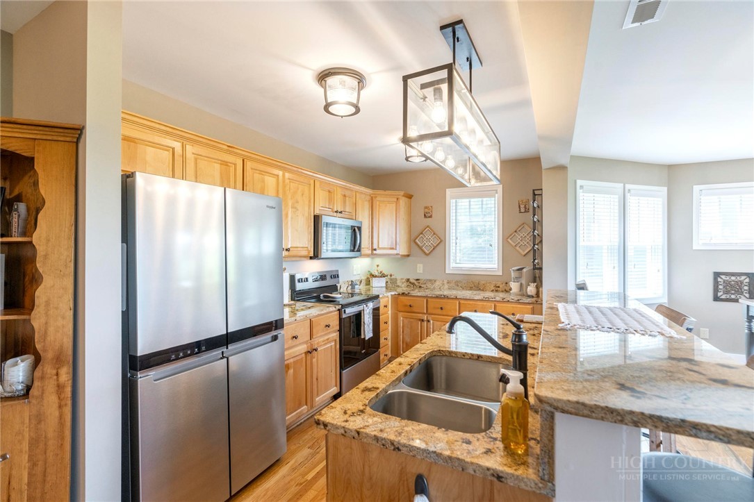 942 Ridge Haven Parkway, Unit R1211 Banner Elk, NC 28604 - Photo 7 of 45 a kitchen with granite countertop a refrigerator a sink a stove and cabinets