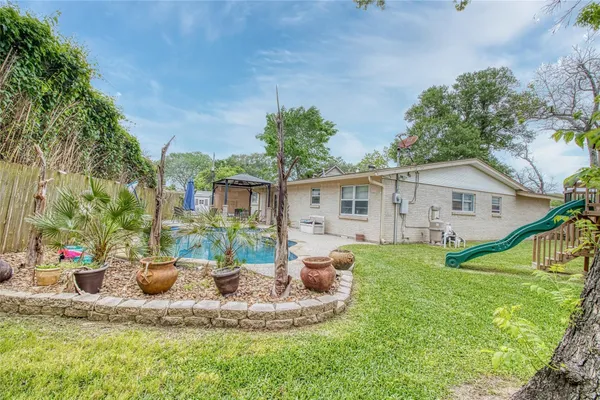 a backyard of a house with table and chairs plants and large tree