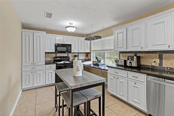 a kitchen with granite countertop white cabinets and stainless steel appliances