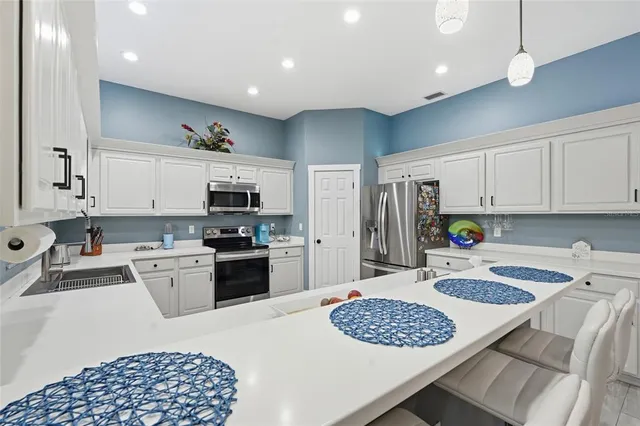 a kitchen with stainless steel appliances granite countertop a stove top oven a sink a refrigerator and white cabinets
