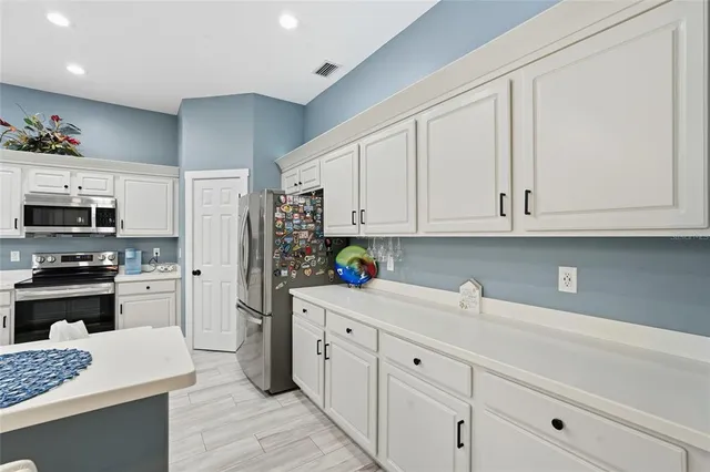a kitchen with stainless steel appliances granite countertop a sink dishwasher stove and white cabinets with wooden floor