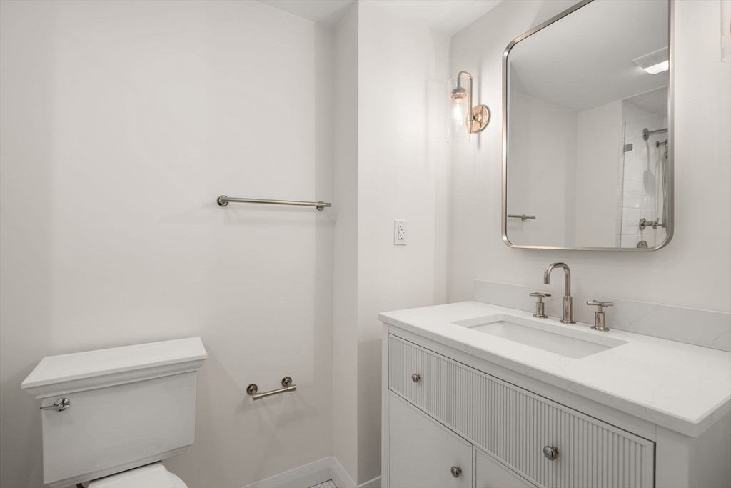 75 Grove Street, Unit 429 Wellesley, MA 02482 - Photo 12 of 22 a bathroom with a sink a toilet and a mirror