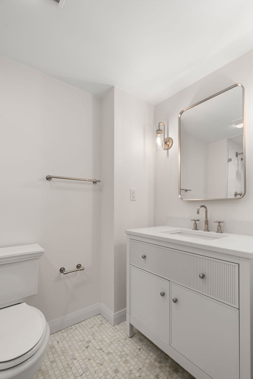 75 Grove Street, Unit 429 Wellesley, MA 02482 - Photo 13 of 22 a bathroom with a toilet a sink a mirror and vanity