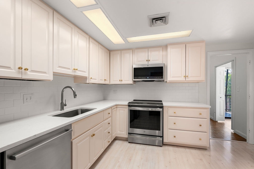 75 Grove Street, Unit 429 Wellesley, MA 02482 - Photo 6 of 22 a kitchen with white cabinets stainless steel appliances and sink
