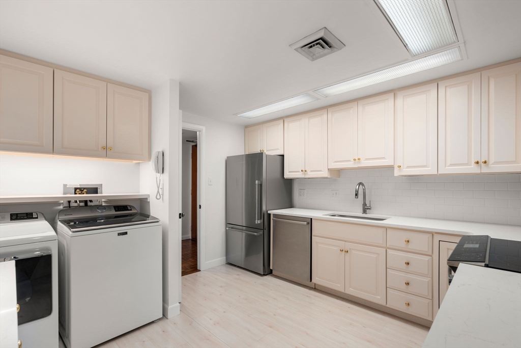 75 Grove Street, Unit 429 Wellesley, MA 02482 - Photo 7 of 22 a kitchen with white cabinets and stainless steel appliances