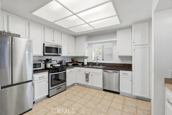 a kitchen with granite countertop white cabinets and stainless steel appliances