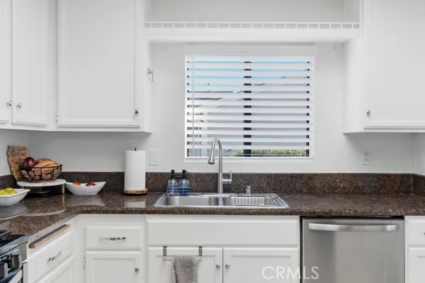 a kitchen with granite countertop white cabinets and a sink