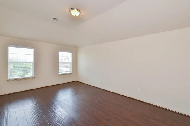 an empty room with wooden floor and windows